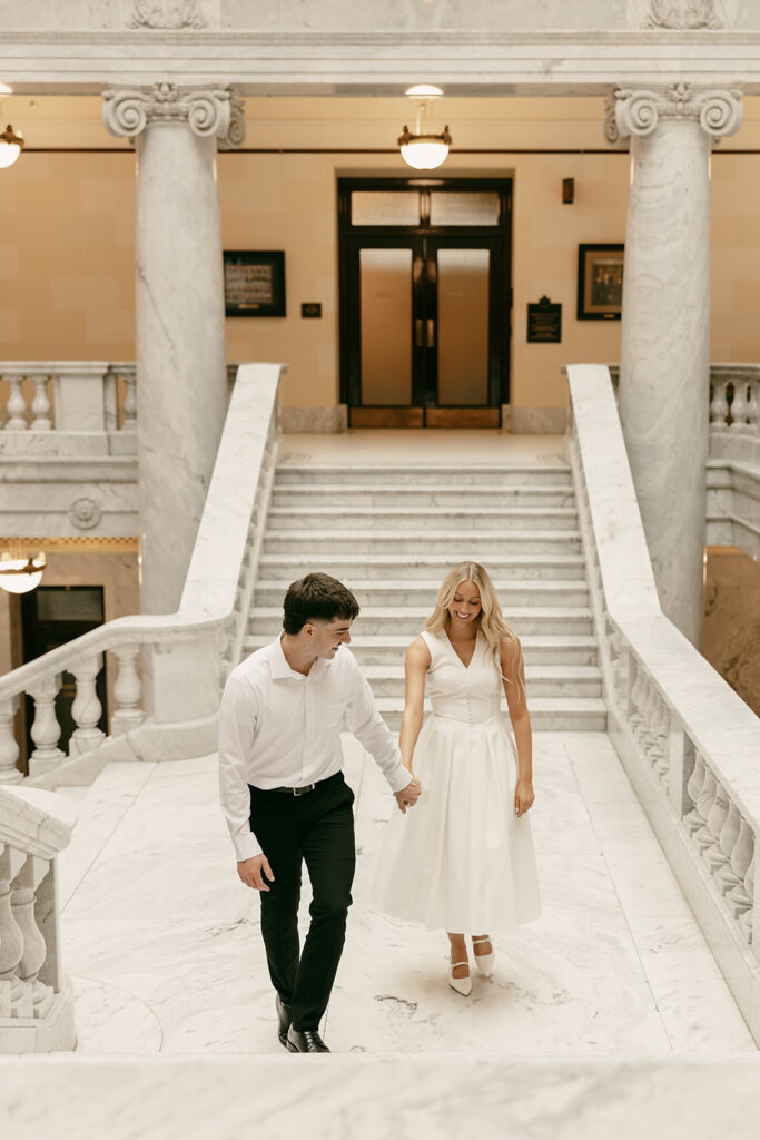 Couple walking up marble stairs inside Utah State Capitol