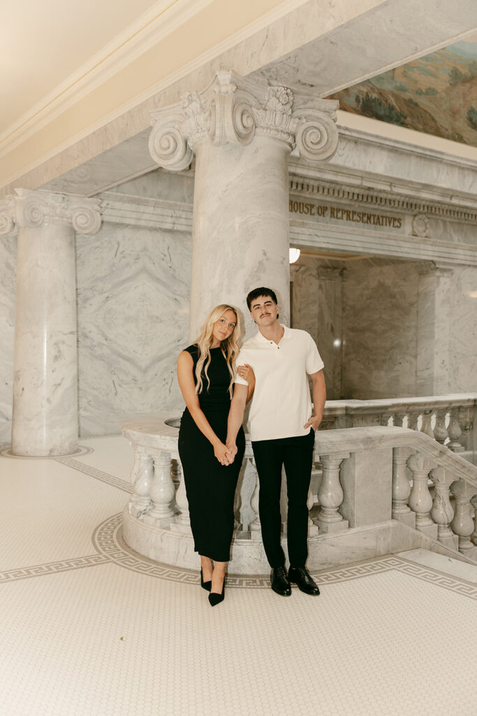 Couple standing together under ornate marble columns, holding hands