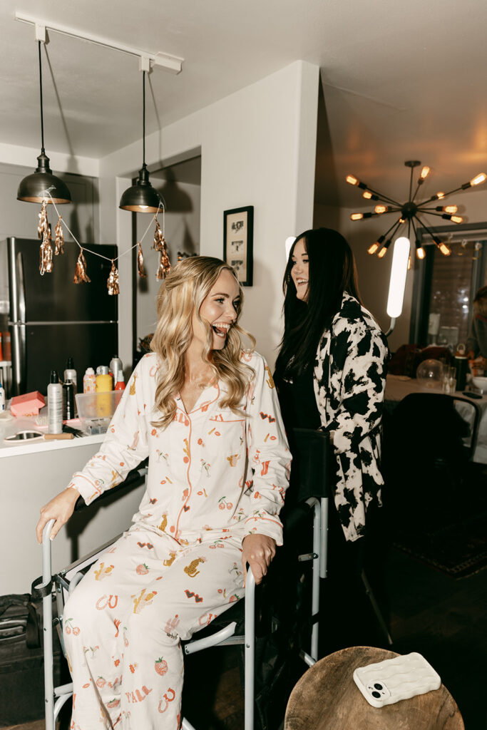 Bride laughs with hair stylist in getting ready suite at her Jackson Hole Cloudveil wedding