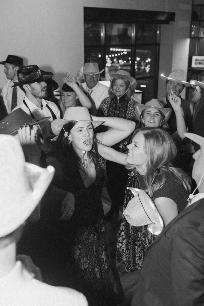 Guests wearing cowboy hats dance and celebrate during the wedding reception