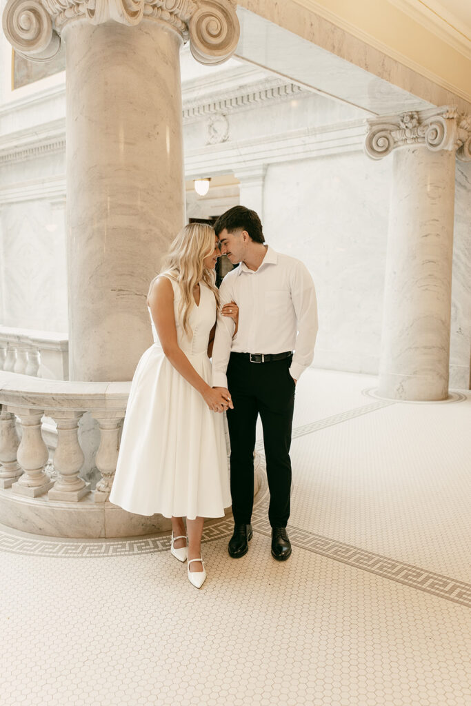 Salt Lake engagement photography with couple leaning close by Capitol columns