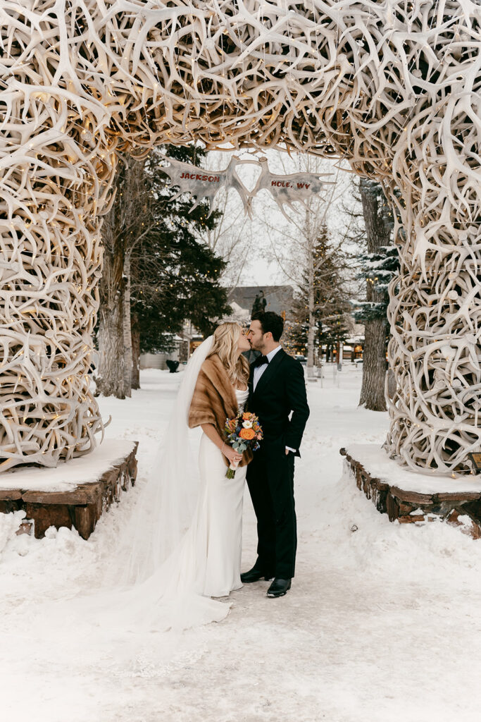 Couple kisses beneath the iconic Jackson Hole antler arch after the ceremony