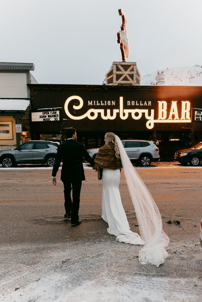 Bride and groom walk hand in hand outside the Million Dollar Cowboy Bar