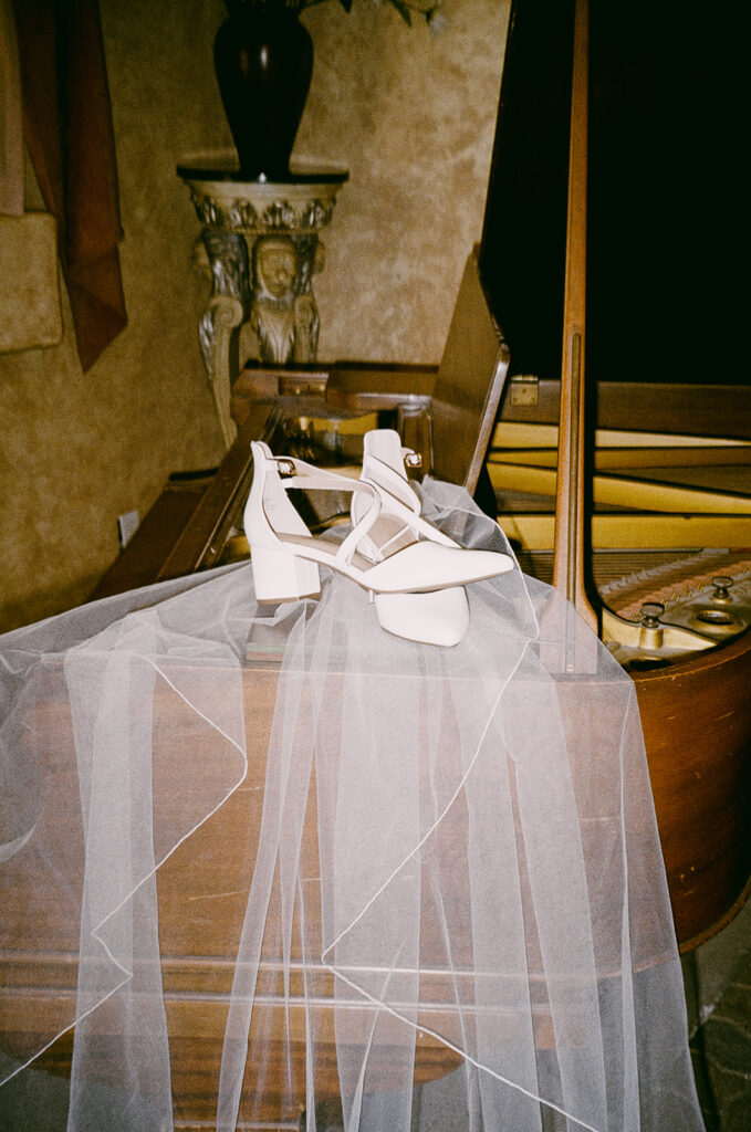 Bridal shoes rest on a piano with a veil draped over, styled for detail shots from a Sonoma County destination wedding