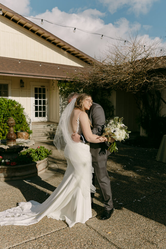 Bride embraces her father with a smile during a heartfelt pre-ceremony moment.