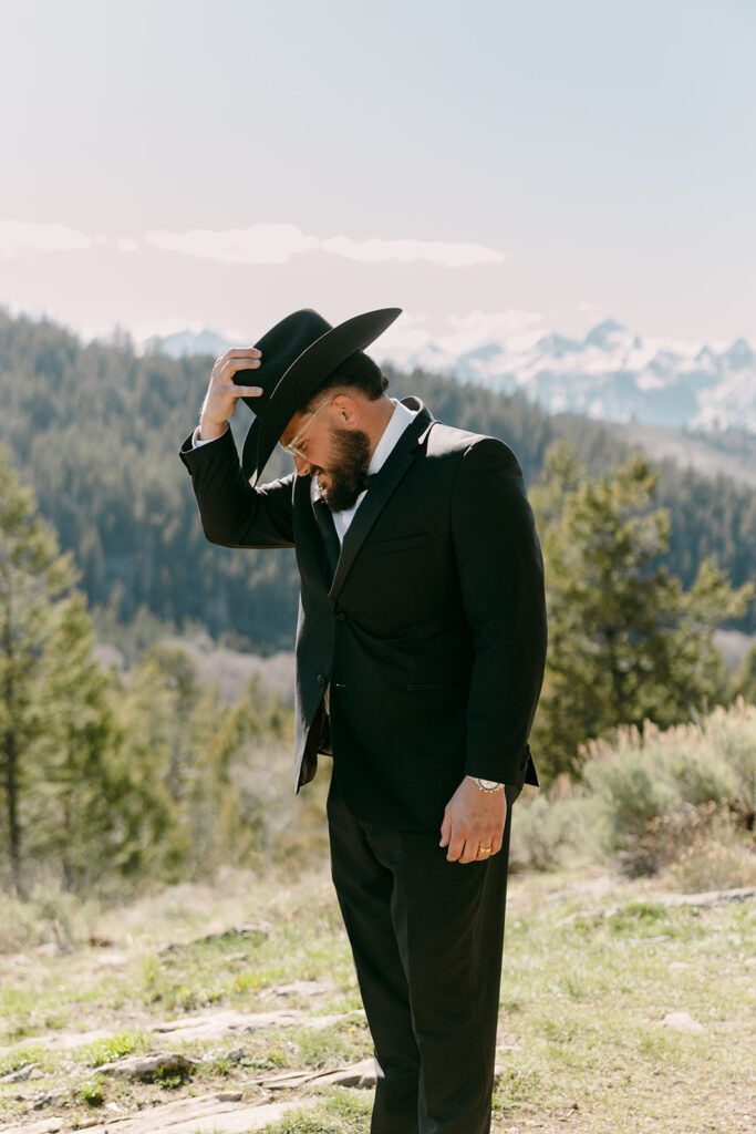 Groom tips his hat in a candid moment before the ceremony begins.