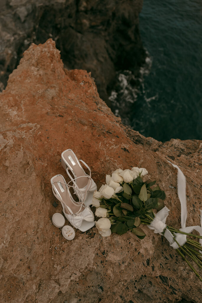 Bridal bouquet, rings, and heels styled on a seaside cliff for a Cartagena destination luxury elopement
