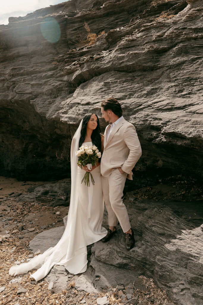 Newlyweds pose by dramatic cliffside during their Cartagena destination luxury elopement