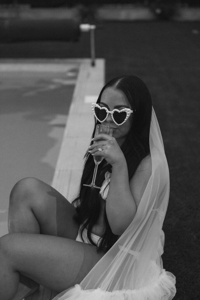 Bride in heart-shaped glasses sips champagne poolside during Cartagena destination luxury elopement