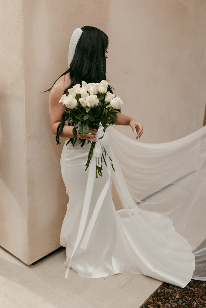 Bride stands in fitted gown, holding bouquet, veil flowing before Cartagena destination luxury elopement
