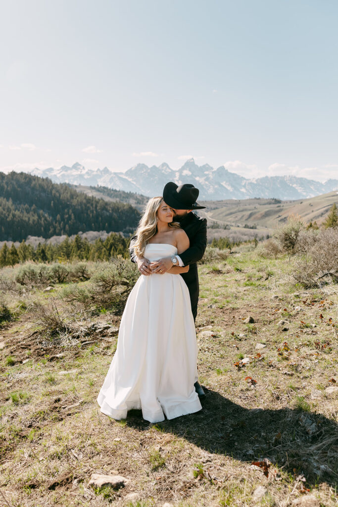 Couple kissing in open field during a romantic Wyoming Wedding Tree elopement with panoramic mountain views.