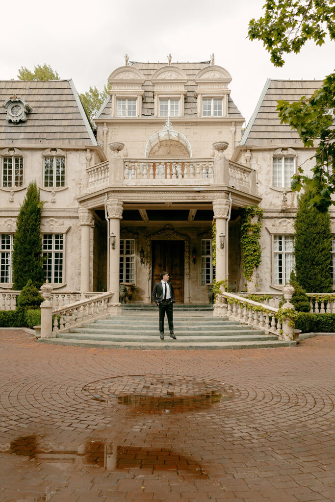 Groom poses solo on the steps in front of La Caille’s timeless European-style venue