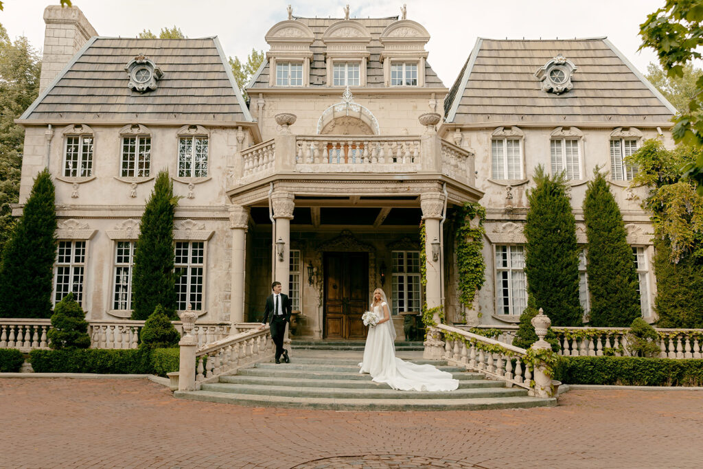 Bride and groom pose on the steps beneath ivy-covered columns at La Caille
