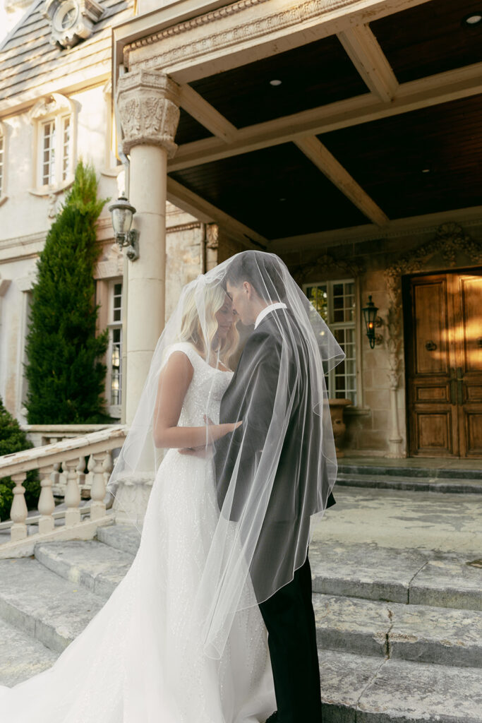 Bride and groom share an intimate moment under her veil