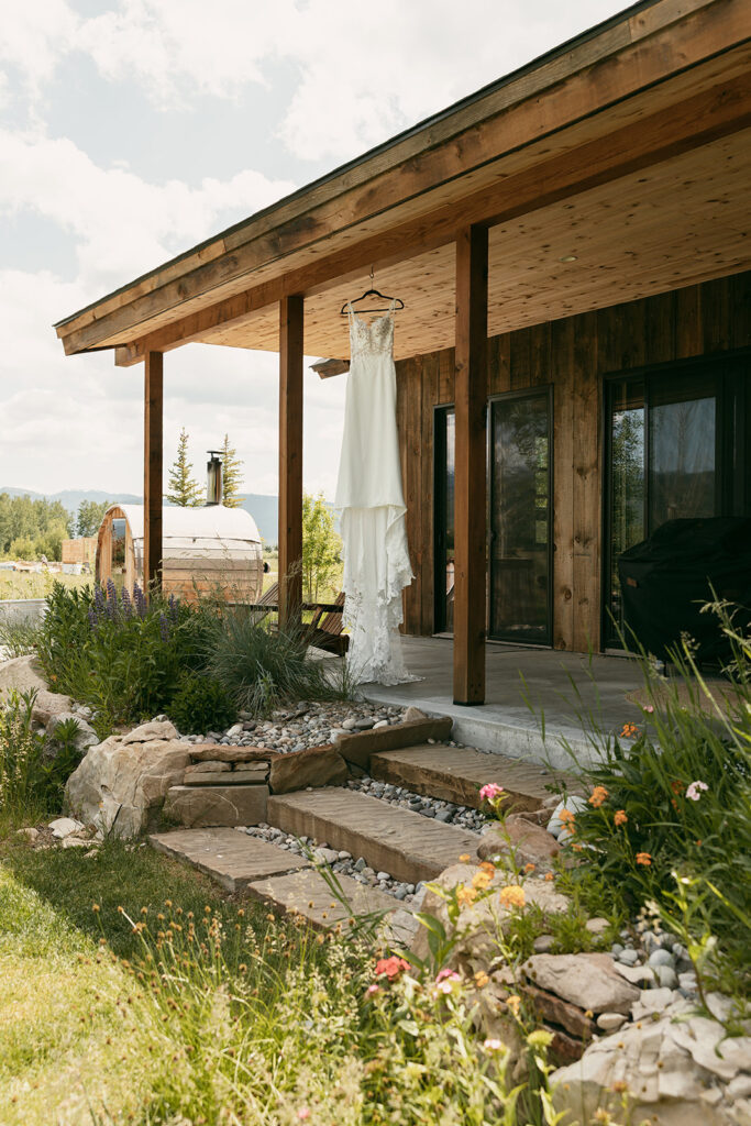 Bridal gown hanging from eaves before Wyoming elopement