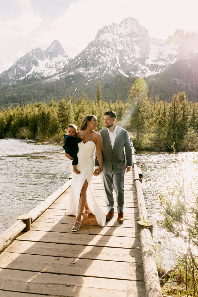 Bride and groom look lovingly at each other as they cross bridge during summer elopement in the Tetons