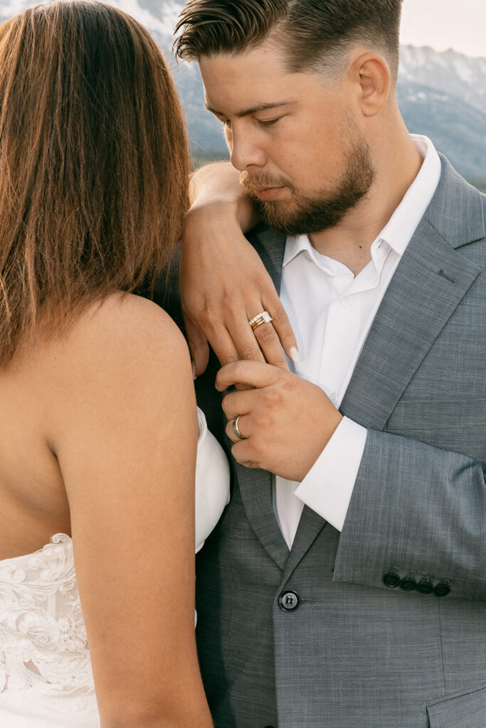 Groom holds bride's hand in Grand Teton National Park, showing both their rings