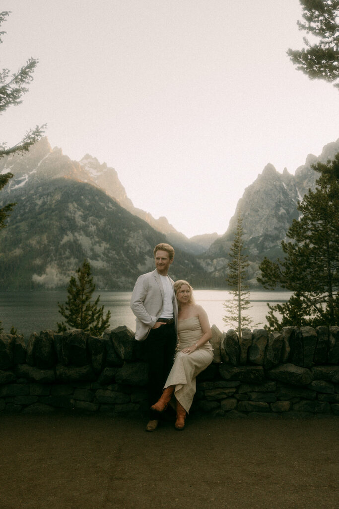 Engaged couple look into the distance with Grand Tetons mountain range in background