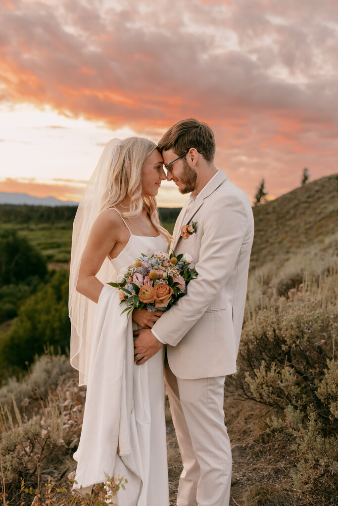 Bride and groom embrace in front of Grand Teton summer sunset