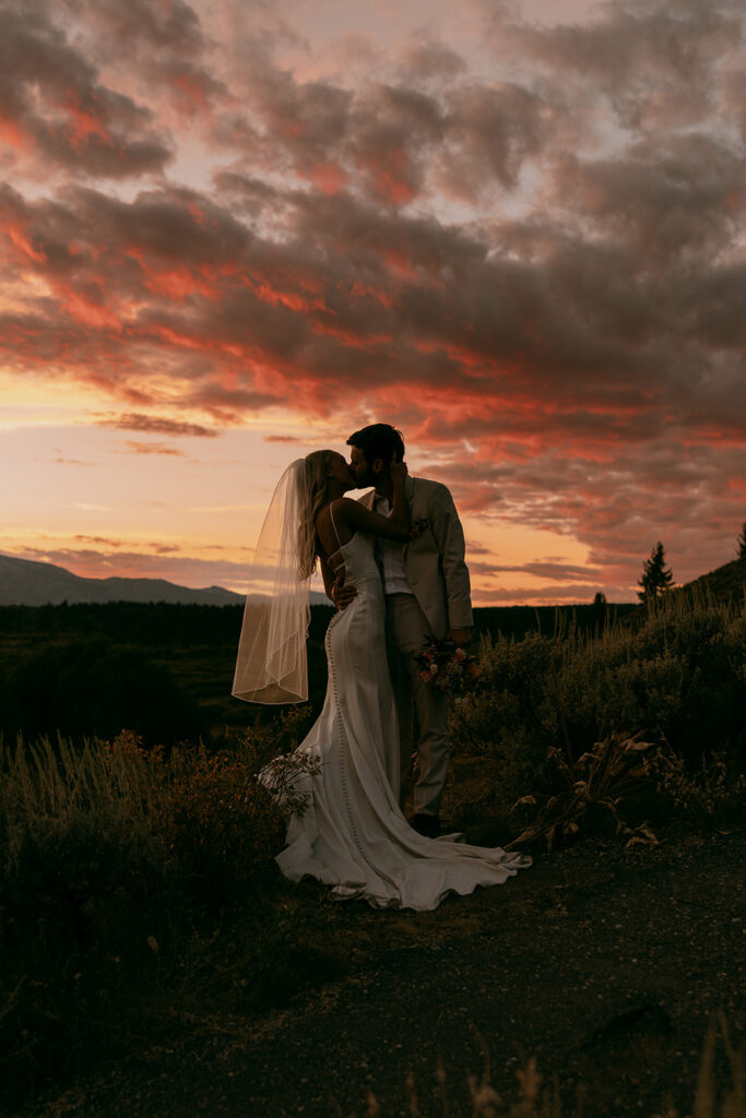 Shadowed sunset silhouette of newlyweds kissing at Jackson Lake Lodge wedding