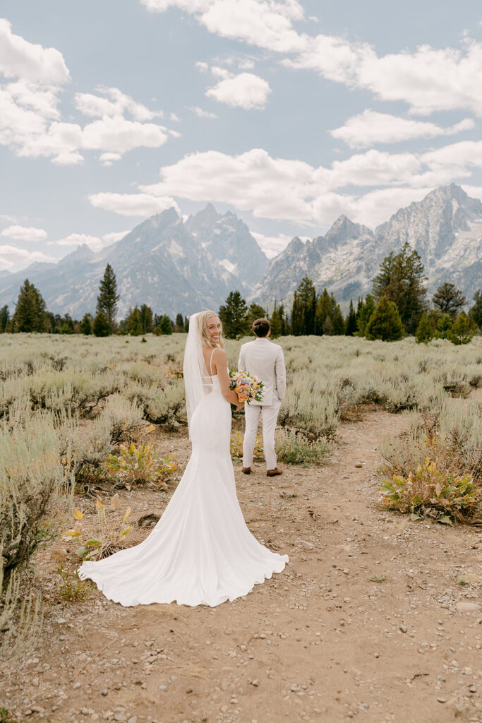 Bride looks of her shoulder before wyoming destination wedding first look