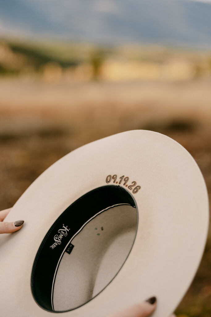 Custom felt hat embroidered with wedding date, captured during Grand Tetons engagement photography in Jackson Hole.