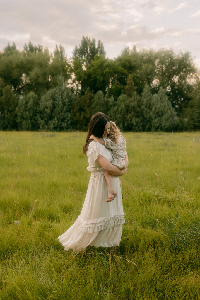 Mother holds daughter in a long dress during Idaho Falls family photographer session.