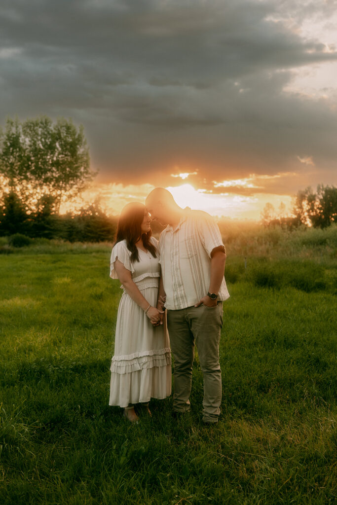 Husband and wife stand in golden light at sunset during a family session in Idaho Falls.