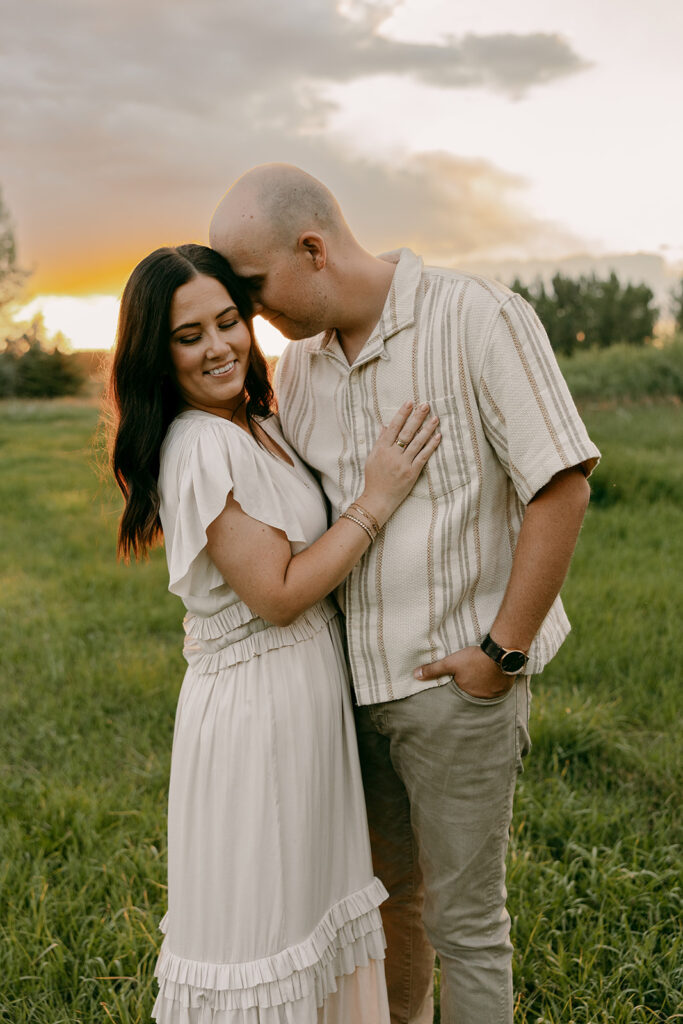 Parents embracing at sunset in a grassy Idaho field during relaxed family portraits.