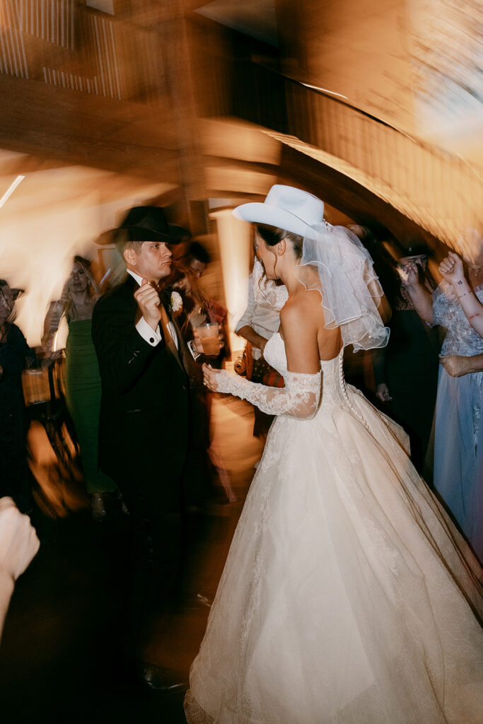Bride and groom dance with cowboy hats on during Jackson Hole reception.
