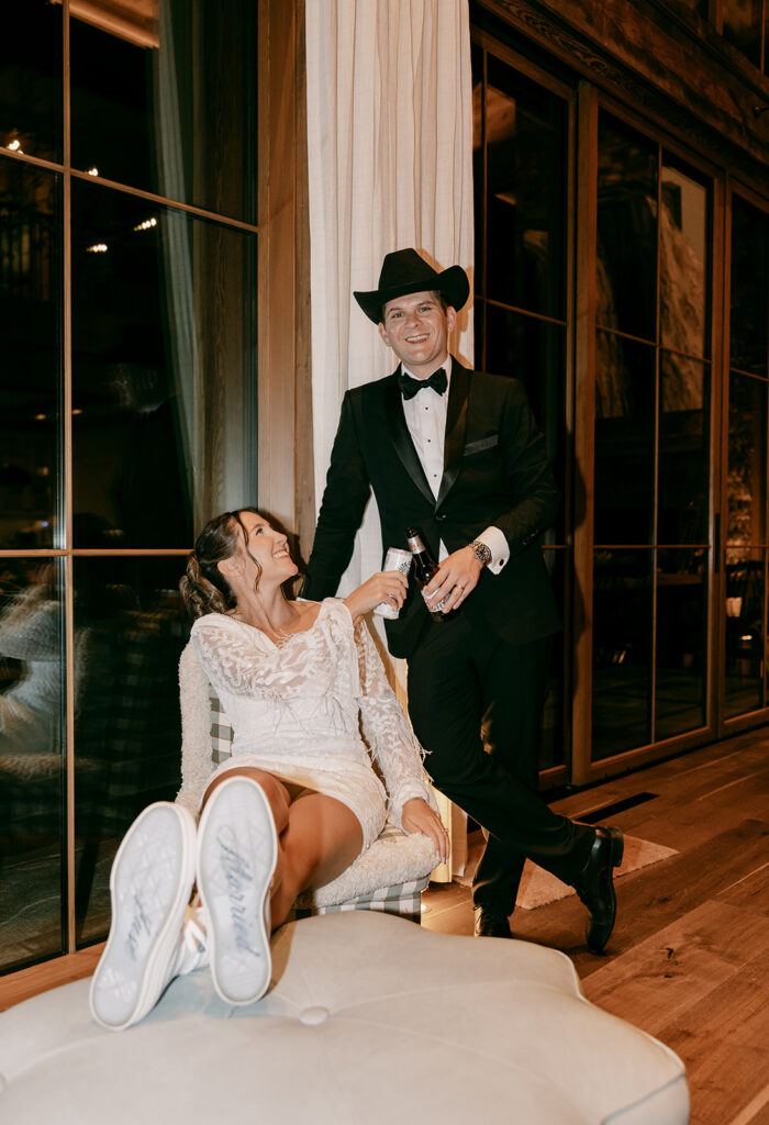 Groom stands behind seated bride after she changes into wedding reception dress.