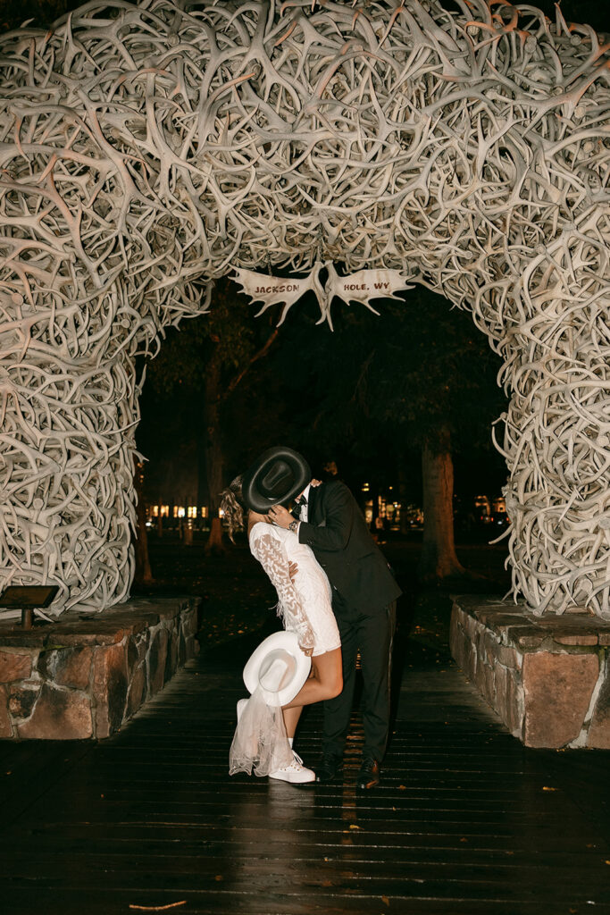 Bride and groom kiss under Jackson Hole antler arch.